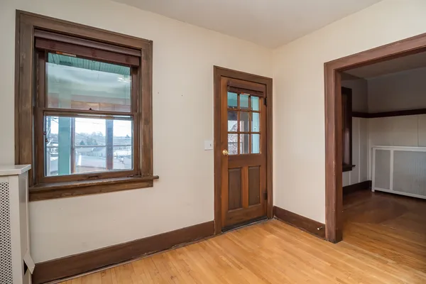 a view of an empty room with wooden floor and a window