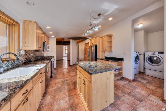 423 Amber Lane Moab, UT 84532 - Photo 22 of 63 Kitchen with light wood finish cabinets, open shelves, separate washer and dryer, stainless steel appliances, and a center island