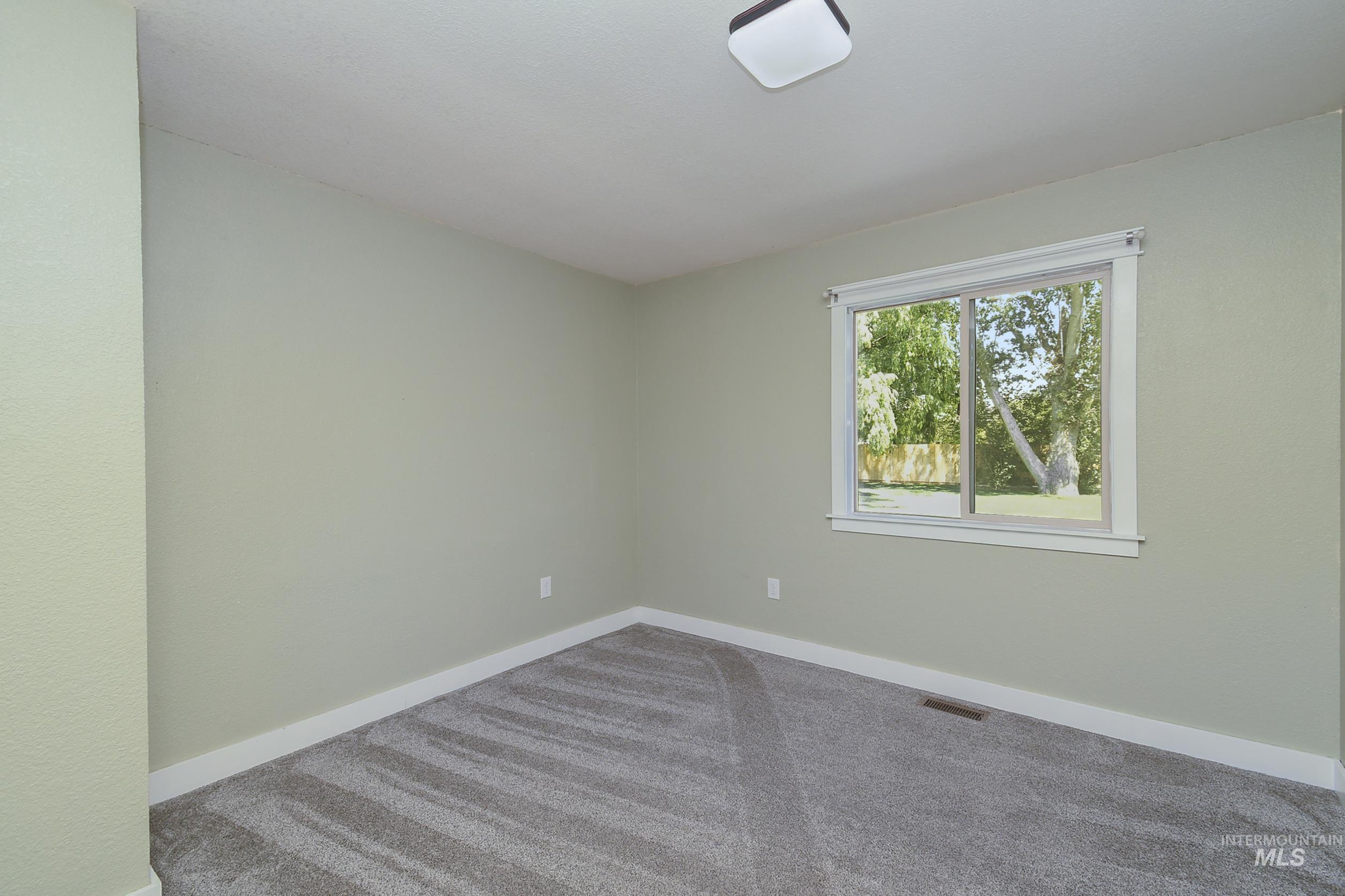 1108 East Ustick Road Caldwell, ID 83607 - Photo 20 of 30 Room featuring light green painted walls, white baseboards, and gray patterned carpeting