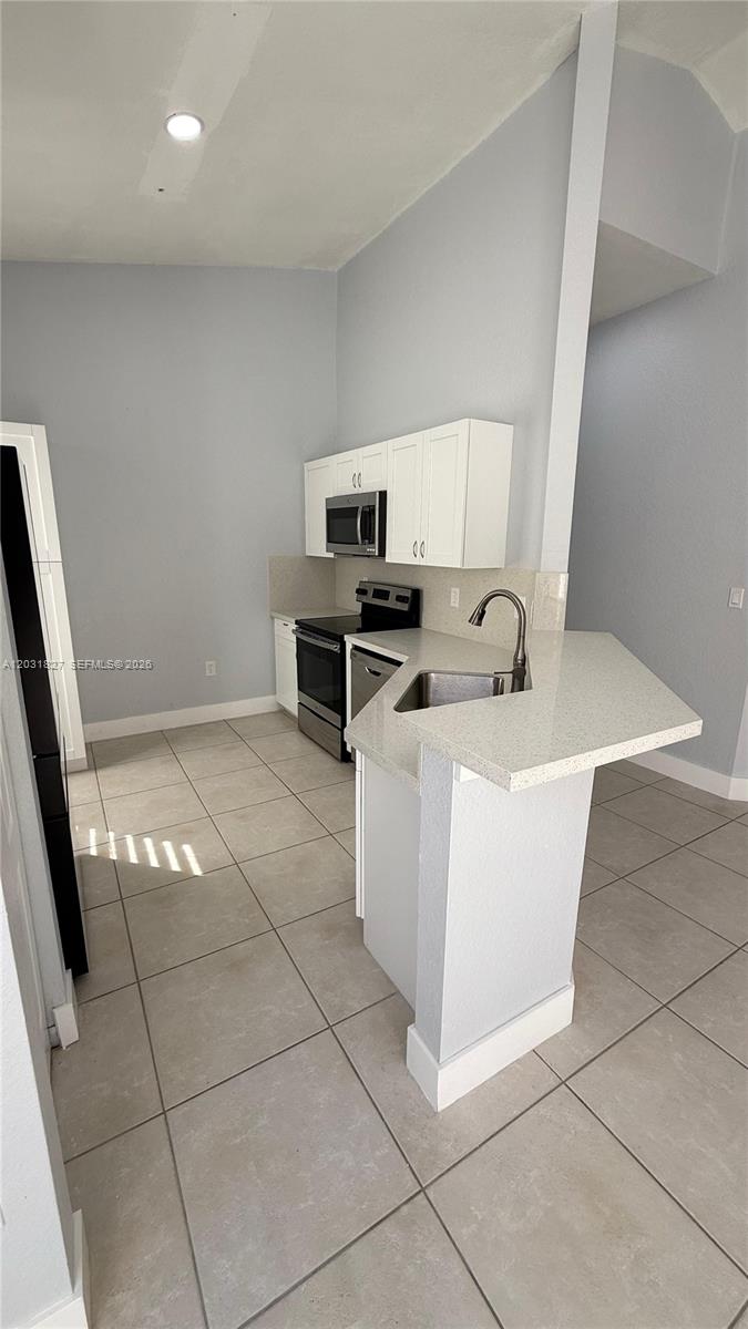 2120 Northeast 37th Road, Unit 1 Homestead, FL 33033 - Photo 17 of 30 a kitchen with stainless steel appliances a sink a stove a microwave a sink a counter top space and cabinets