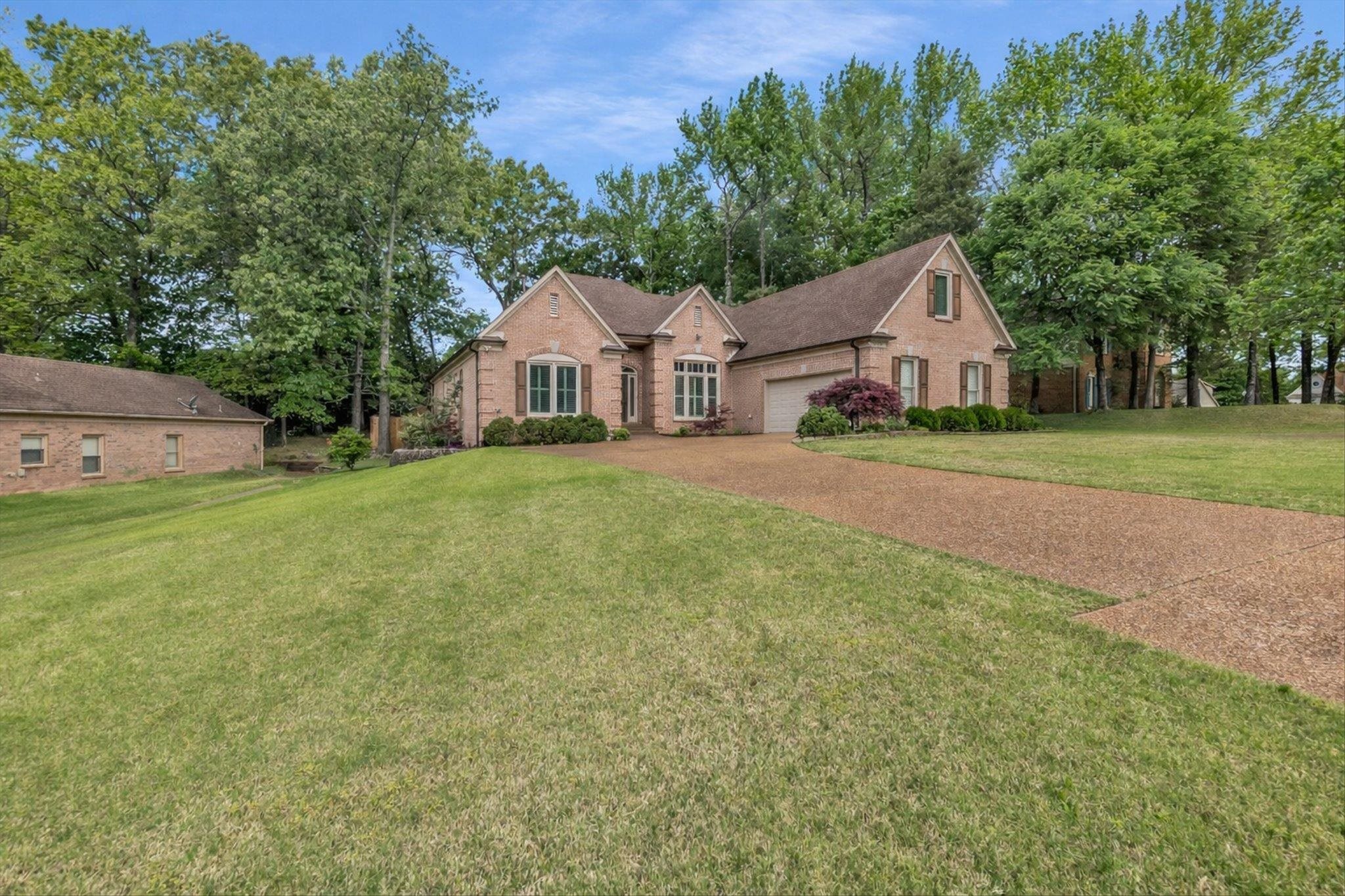 8786 Stablemill Lane Memphis, TN 38016 - Photo 2 of 40 a view of a large house with a big yard and large trees
