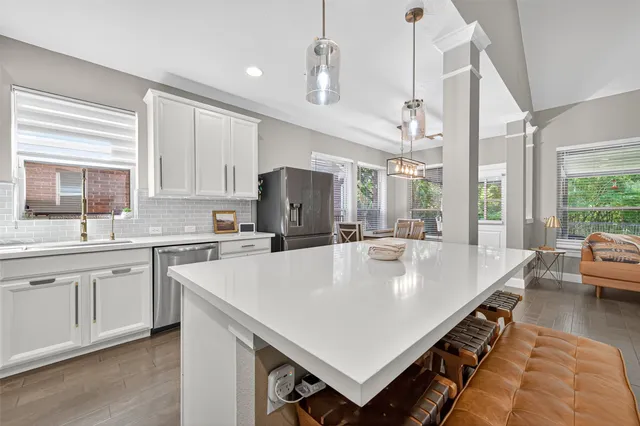 a large white kitchen with a stove a sink dishwasher and a refrigerator with wooden floor