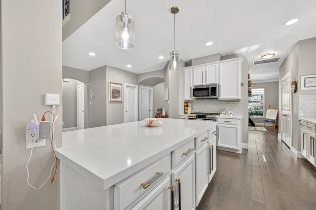 a kitchen with kitchen island a white counter top space cabinets and stainless steel appliances