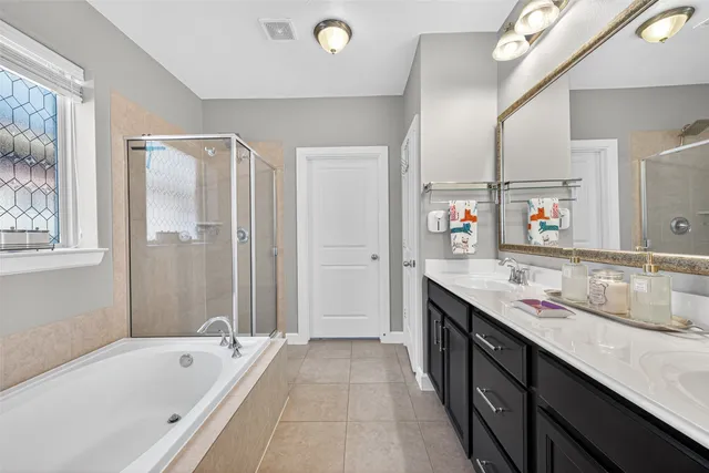 a bathroom with a granite countertop double vanity sink a mirror and a bathtub