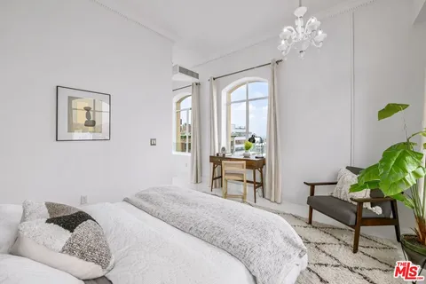 a bedroom with a bed chandelier and a window
