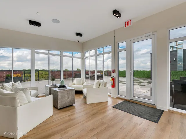 a living room with furniture large windows and wooden floor