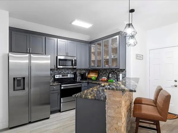 a kitchen with kitchen island a counter top space appliances and a chandelier