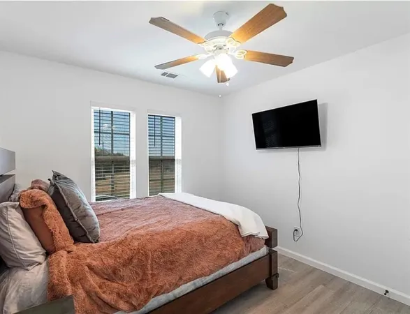 a bedroom with a bed a flat screen tv and a chandelier