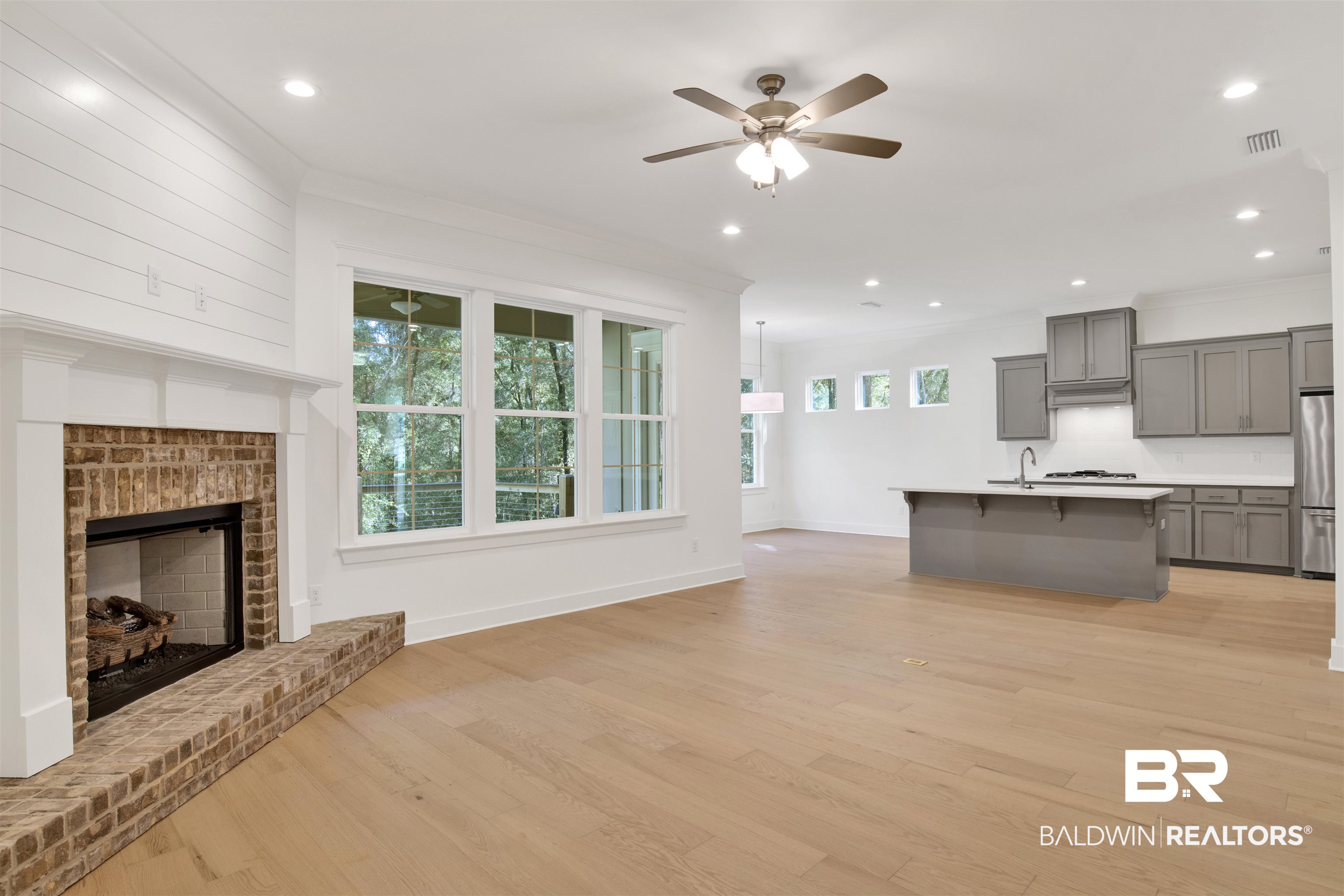 5 Long Leaf Circle Fairhope, AL 36532 - Photo 8 of 44 Unfurnished living room featuring light hardwood / wood-style floors, a brick fireplace, ceiling fan, and crown molding