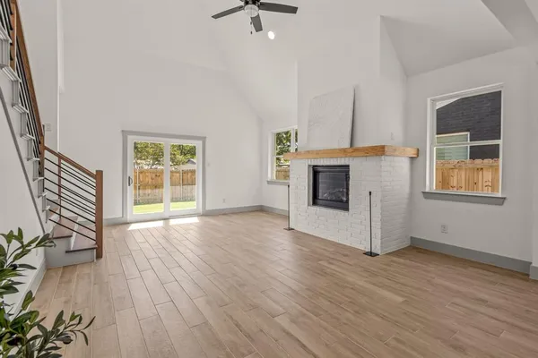 an empty room with wooden floor a fireplace and windows