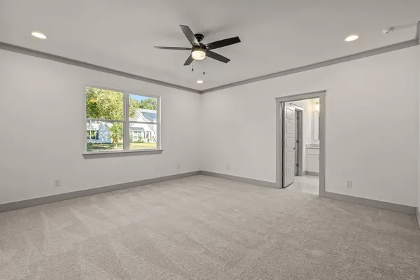 an empty room with ceiling fan and windows