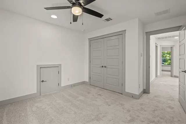 en empty room with closet and a chandelier fan