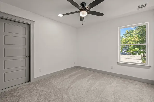 an empty room with a window and a fan