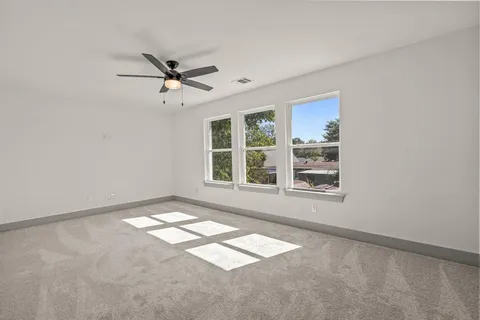 an empty room with windows and fan