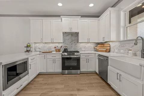a kitchen with granite countertop white cabinets and white stainless steel appliances