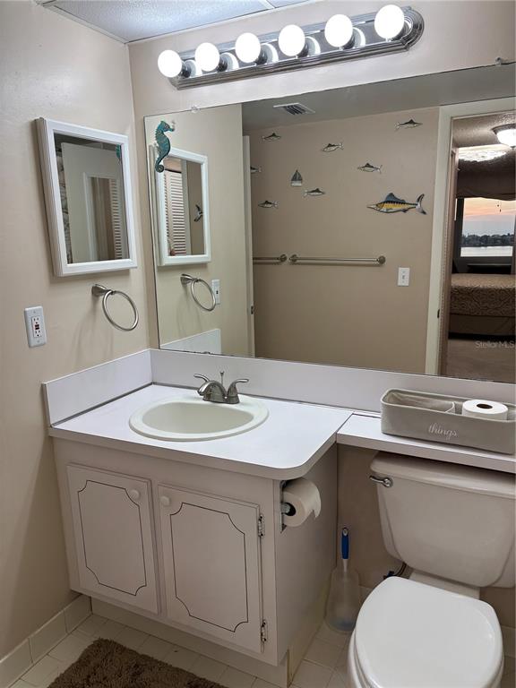 4750 Cove Circle, Unit 904 St. Petersburg, FL 33708 - Photo 20 of 37 a bathroom with a granite countertop toilet sink and mirror