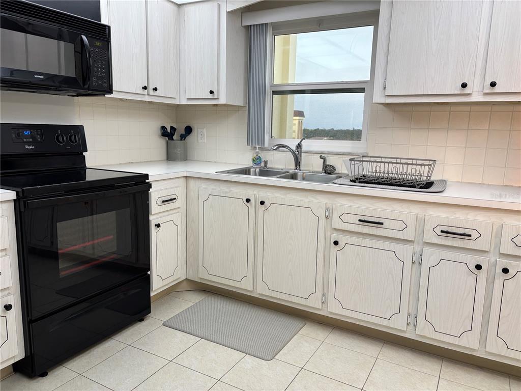 4750 Cove Circle, Unit 904 St. Petersburg, FL 33708 - Photo 10 of 37 a kitchen with white cabinets stainless steel appliances and sink