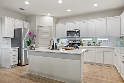 a kitchen with kitchen island granite countertop a sink cabinets and stainless steel appliances