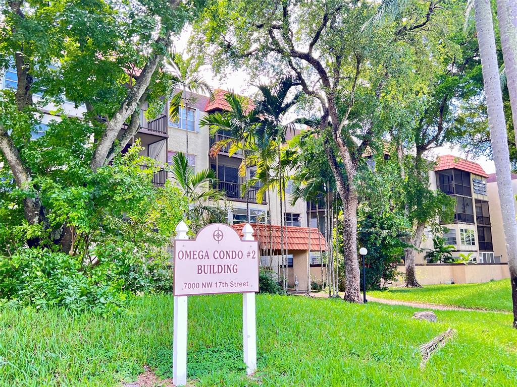 a sign that is sitting in front of a house with a tree