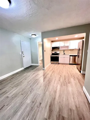 an empty room with wooden floor fireplace and windows