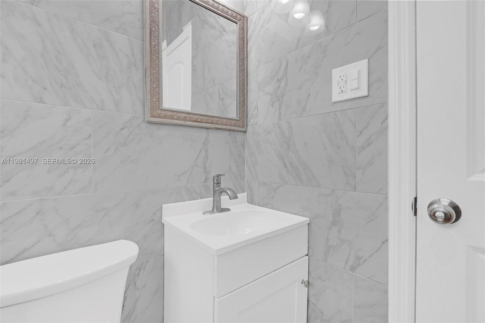 369 Phippen Waiters Road, Unit 2 Dania Beach, FL 33004 - Photo 14 of 18 a bathroom with a sink a toilet and a mirror