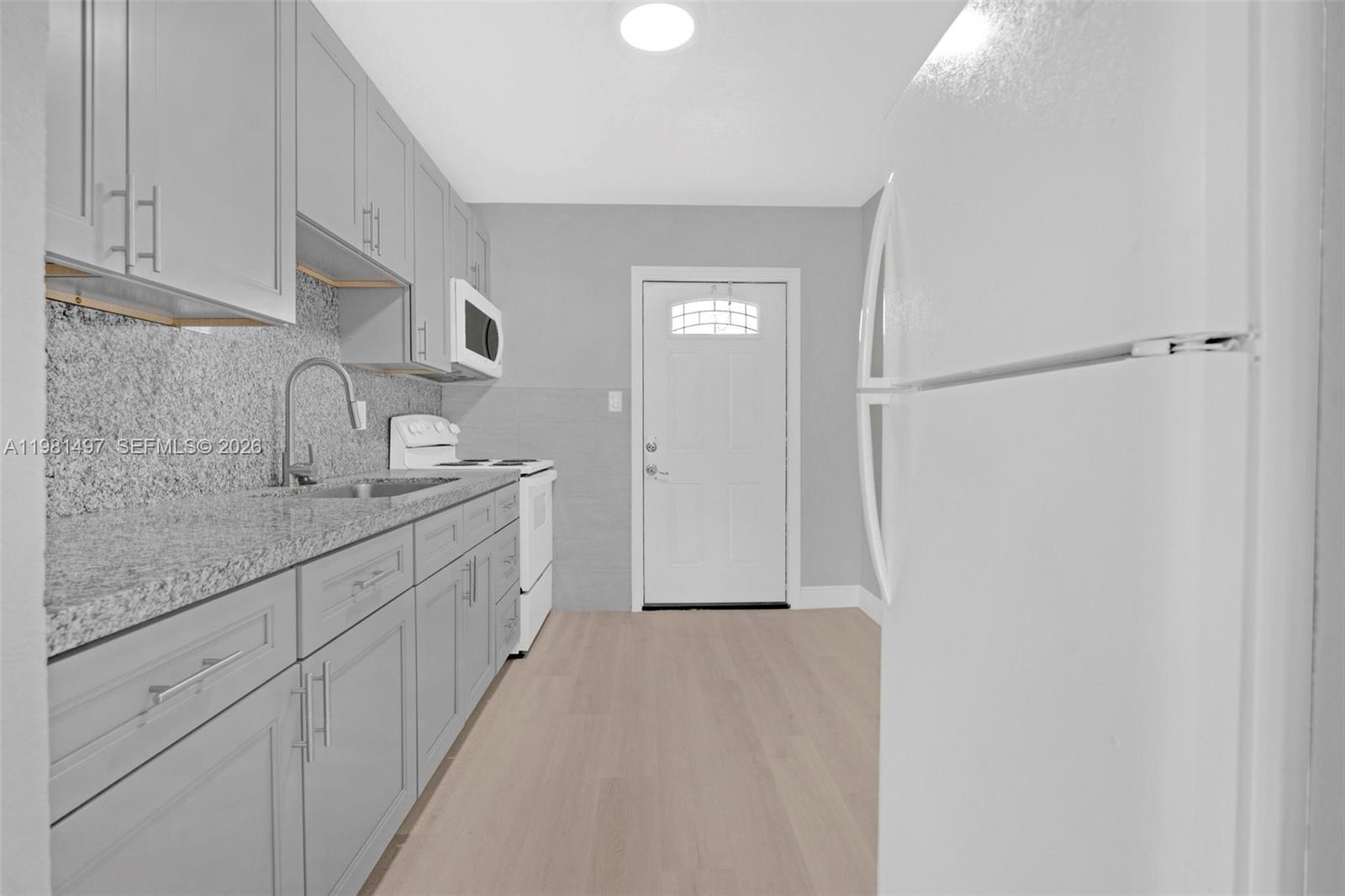 369 Phippen Waiters Road, Unit 2 Dania Beach, FL 33004 - Photo 5 of 18 a bathroom with a granite countertop sink and a mirror