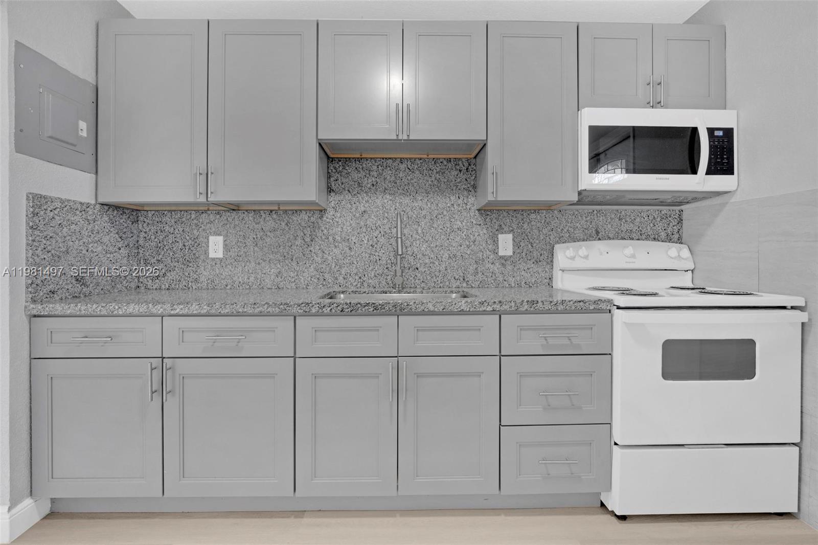 369 Phippen Waiters Road, Unit 2 Dania Beach, FL 33004 - Photo 6 of 18 a kitchen with white cabinets and white appliances