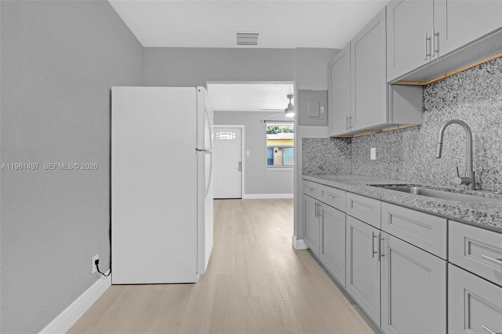 369 Phippen Waiters Road, Unit 2 Dania Beach, FL 33004 - Photo 7 of 18 a kitchen with granite countertop white cabinets and sink