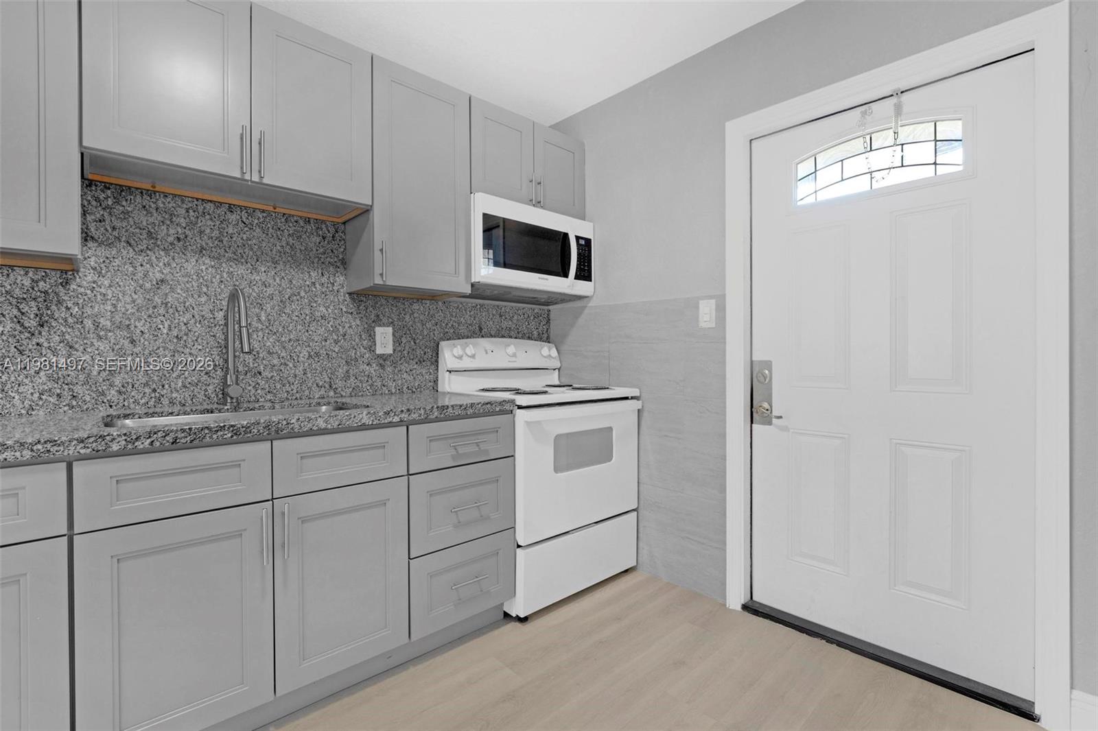 369 Phippen Waiters Road, Unit 2 Dania Beach, FL 33004 - Photo 8 of 18 a kitchen with white cabinets and white appliances