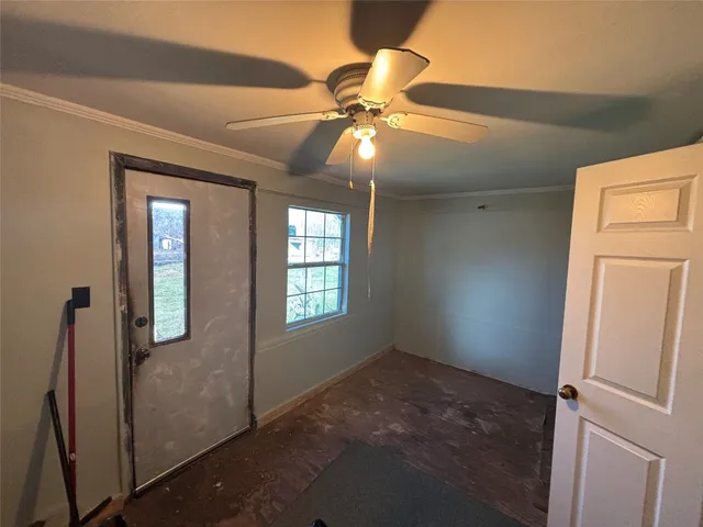 a view of an empty room with window and chandelier fan
