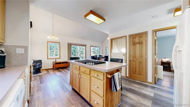 a kitchen with a stove a refrigerator a sink dishwasher and a dining table with wooden floor