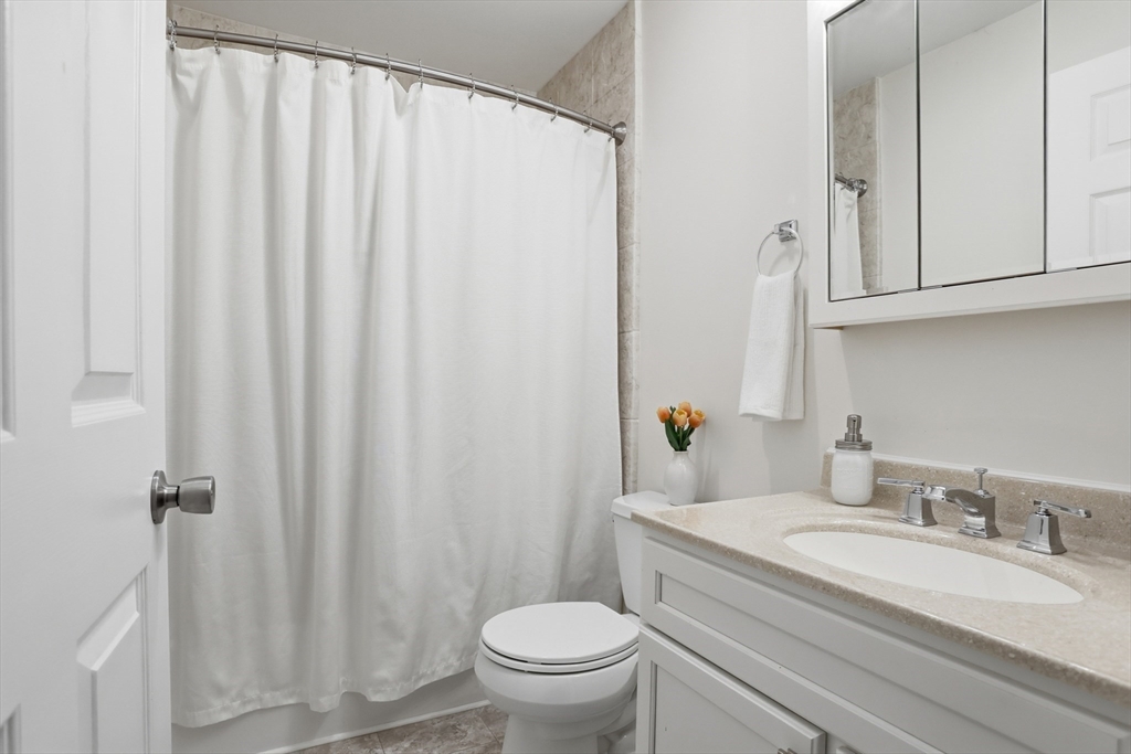 425 Main Street, Unit 22C Hudson, MA 01749 - Photo 16 of 23 a bathroom with a granite countertop sink toilet and a mirror