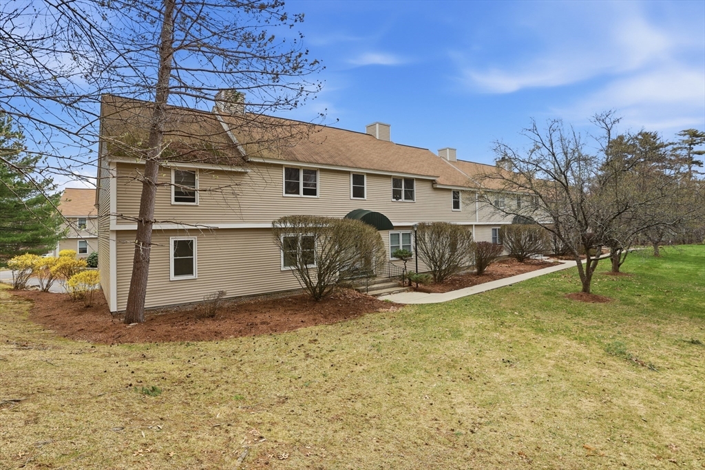 425 Main Street, Unit 22C Hudson, MA 01749 - Photo 19 of 23 a view of a white house with a large tree and a yard