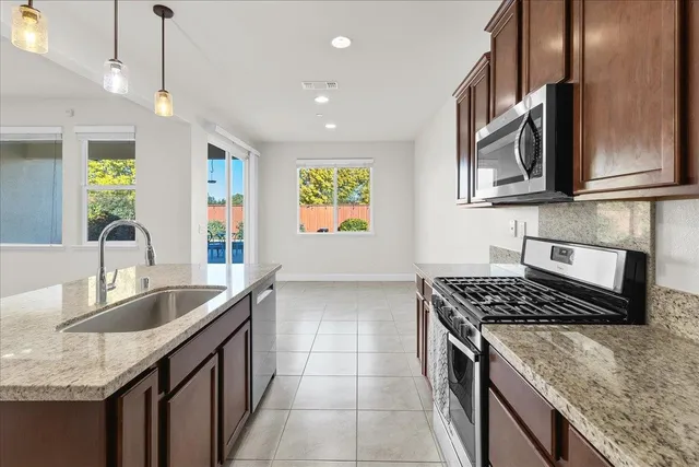 a kitchen with stainless steel appliances granite countertop a sink a refrigerator and a granite counter tops