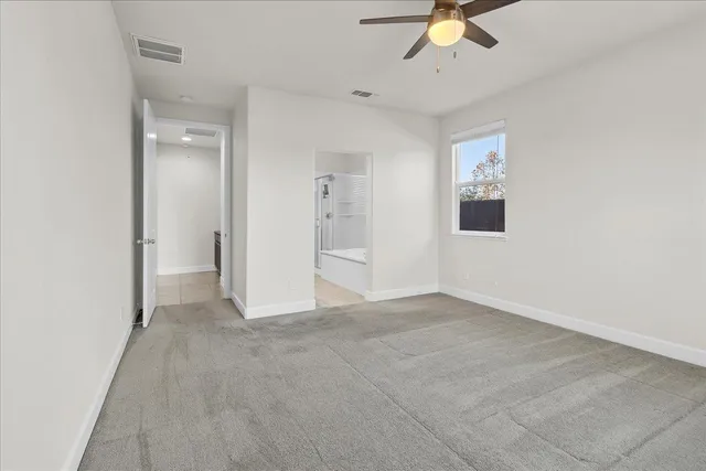 an empty room with chandelier fan and windows
