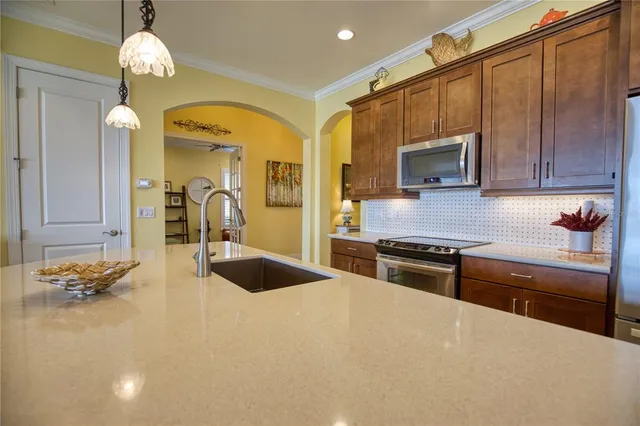 a kitchen with granite countertop a refrigerator oven a sink a dining table and chairs