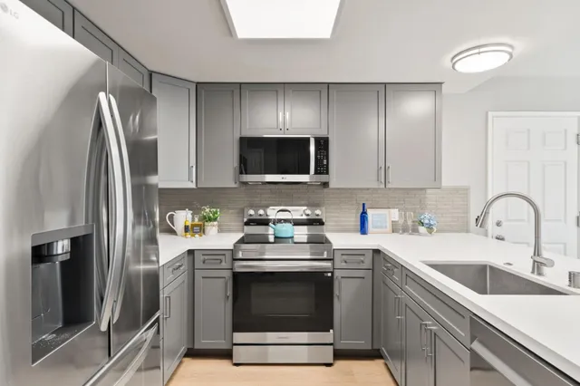 a kitchen with stainless steel appliances a stove a sink a refrigerator a microwave and cabinets