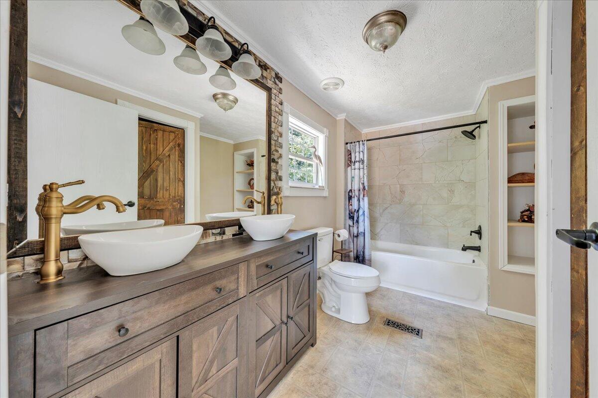 6638 Stewartsville Road Moneta, VA 24121 - Photo 16 of 27 a spacious bathroom with a double vanity sink a toilet a mirror and a bathtub