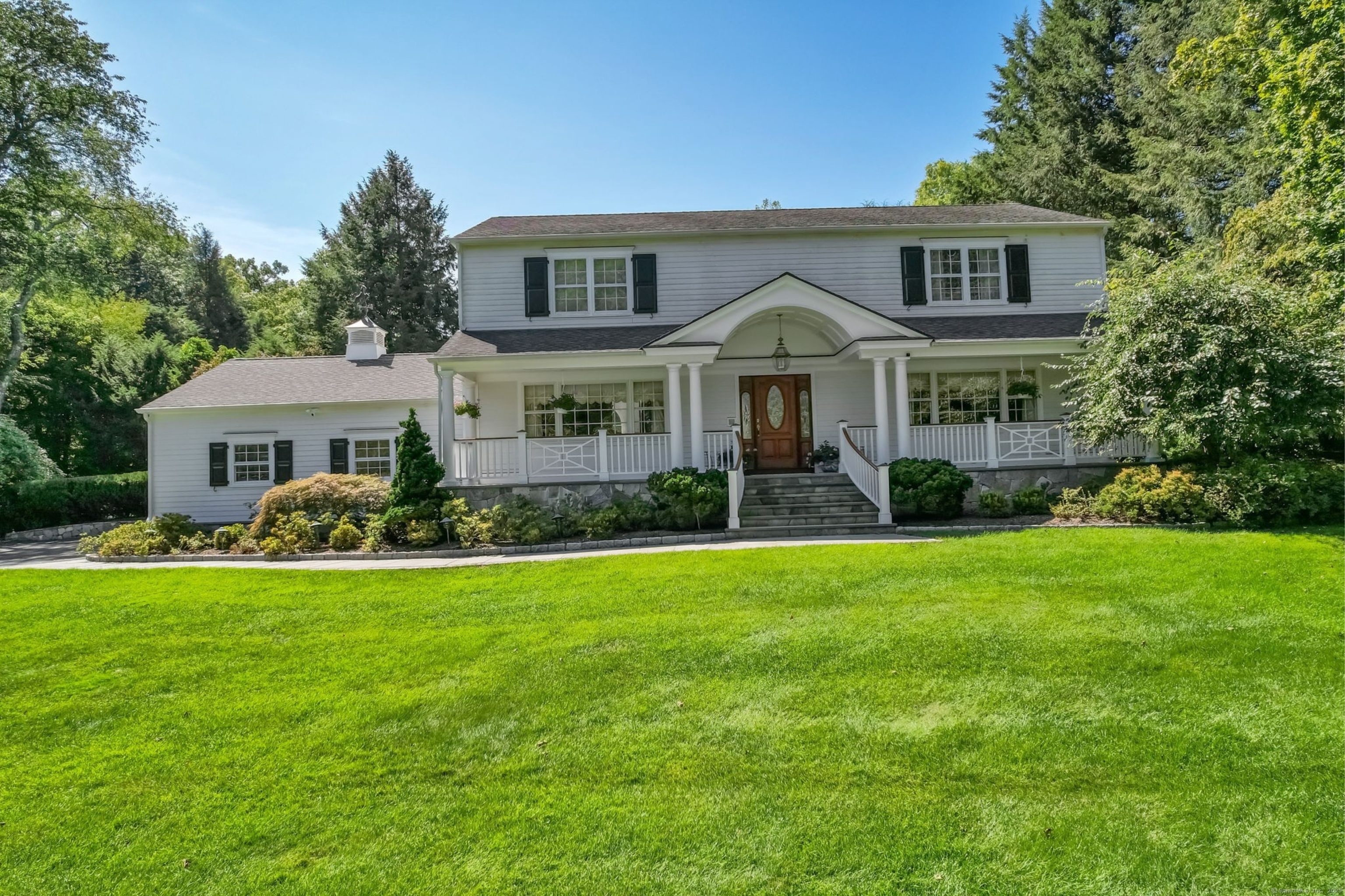 a front view of a house with a garden and trees