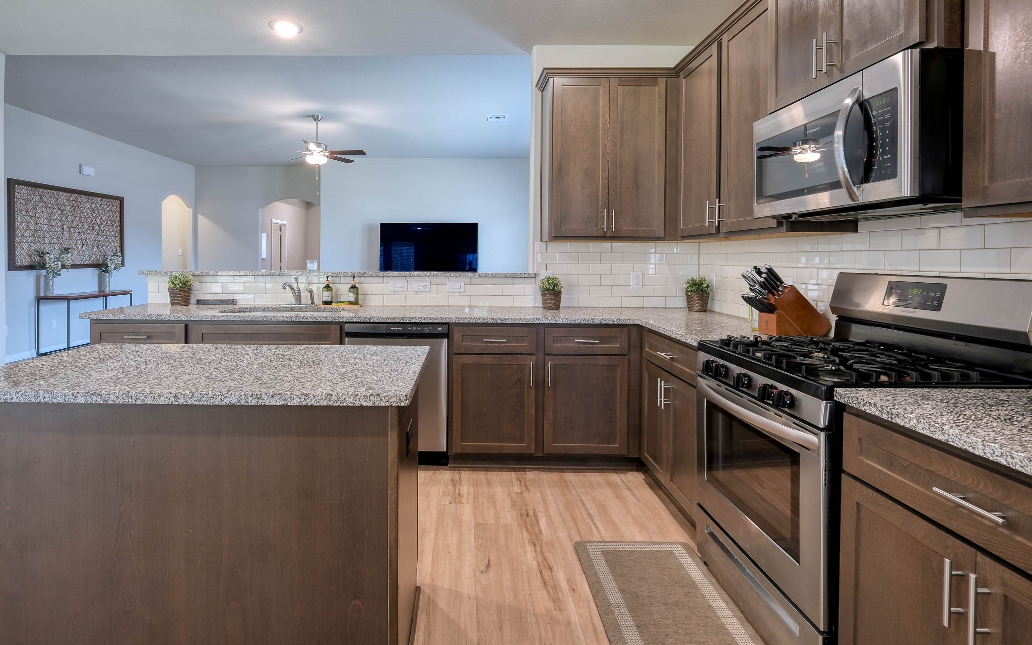 16747 Rockwall Street Conroe, TX 77303 - Photo 18 of 50 a kitchen with stainless steel appliances granite countertop a stove a sink dishwasher and a microwave oven with wooden cabinets