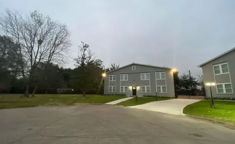 a view of a house with a yard and large tree