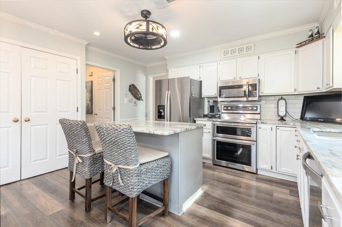 8523 Bazemore Road Memphis, TN 38018 - Photo 14 of 40 a kitchen with stainless steel appliances granite countertop a stove top oven a refrigerator a sink and a dining table with wooden floor