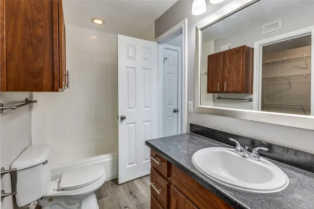 a bathroom with a granite countertop sink a toilet a mirror and shower