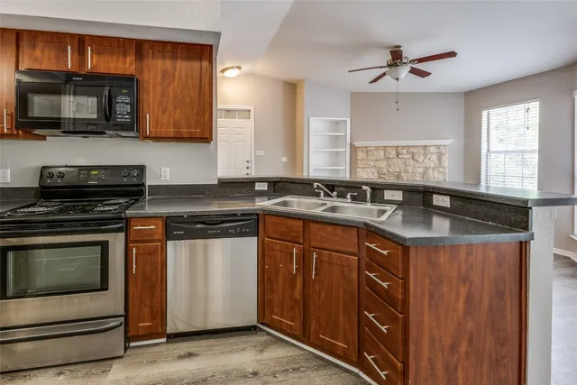 a kitchen with granite countertop a sink cabinets and stainless steel appliances