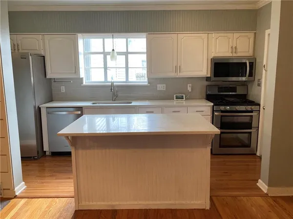 a kitchen with kitchen island a sink dishwasher a stove and a refrigerator with wooden floor