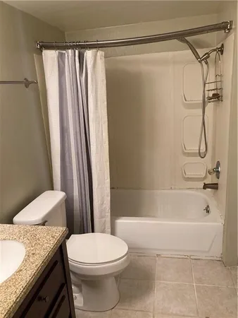 a bathroom with a granite countertop bathtub shower sink vanity and toilet