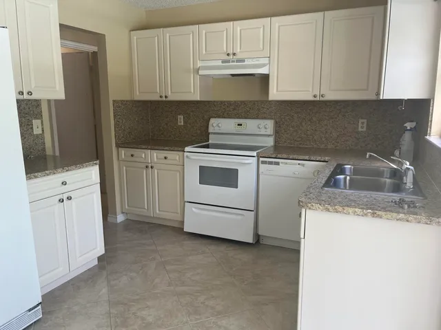 a kitchen with white cabinets and white appliances