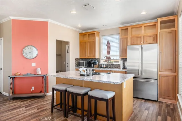 a kitchen with stainless steel appliances granite countertop a stove a refrigerator a sink a dining table and chairs with wooden floor