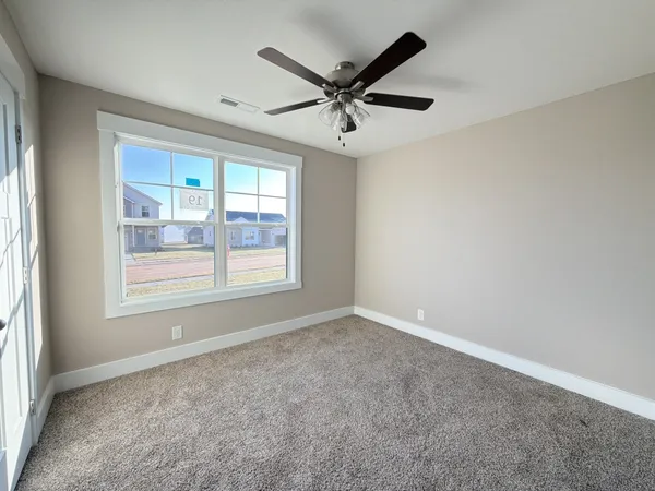an empty room with ceiling fan and windows
