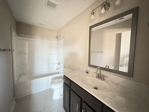 a bathroom with a granite countertop sink a toilet a shower and a mirror